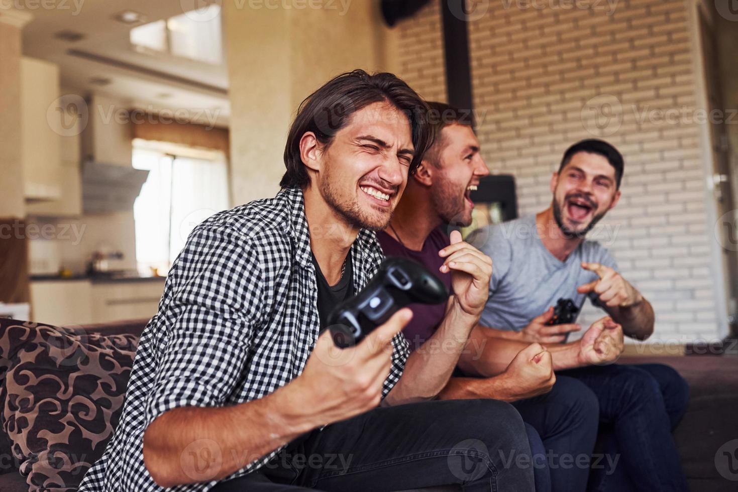 grupp av vänner ha roligt spelar trösta spel inomhus på levande rum foto