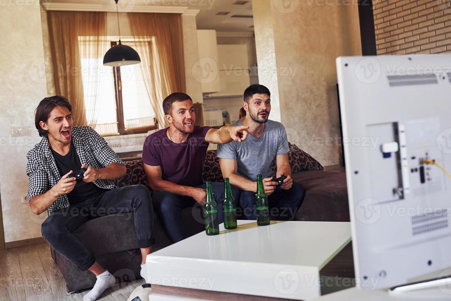 grupp av vänner ha roligt spelar trösta spel inomhus på levande rum foto