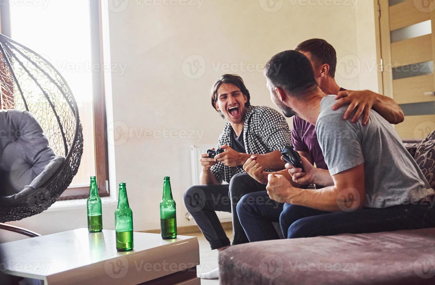grupp av vänner ha roligt spelar trösta spel inomhus på levande rum foto