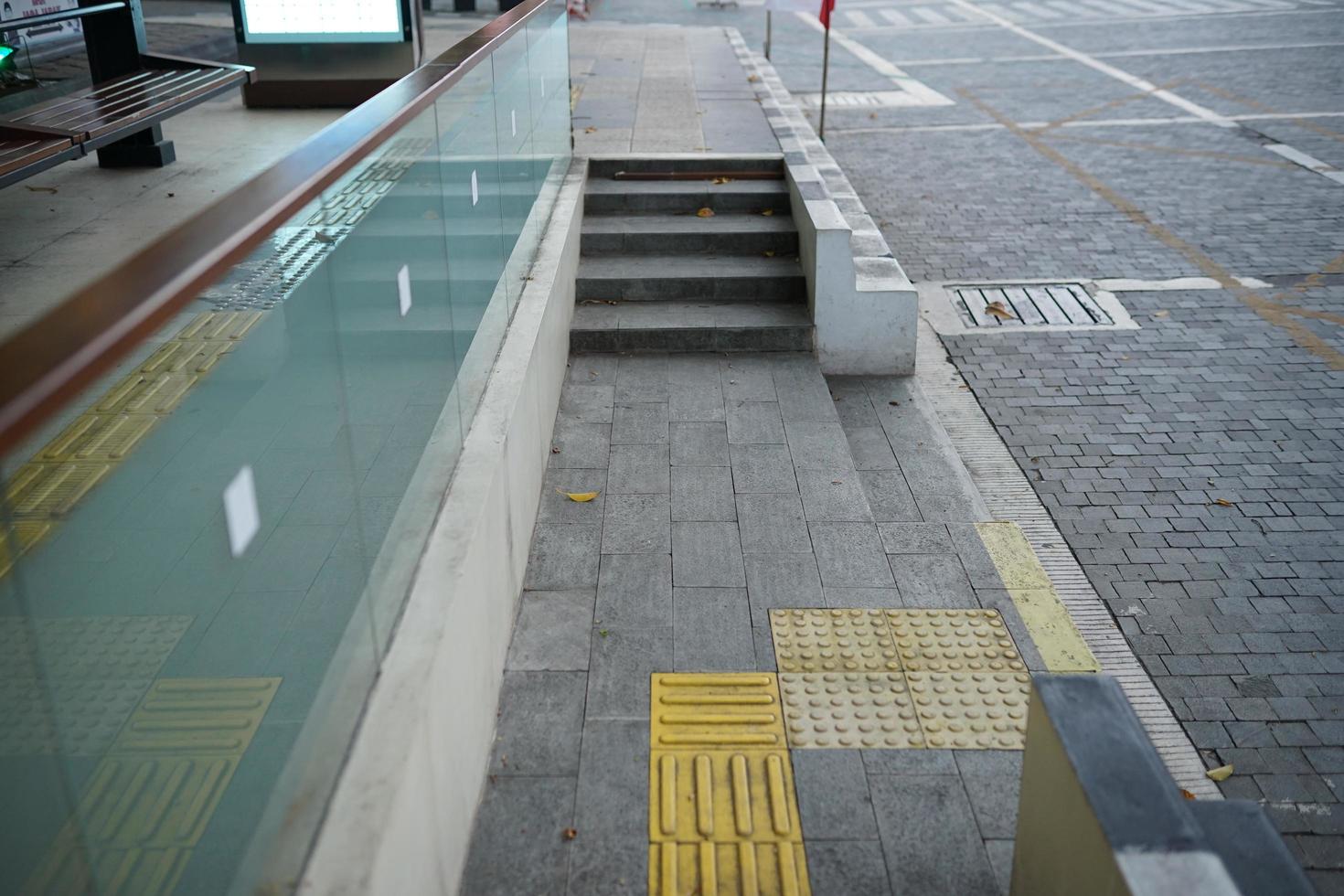 stenläggning trottoar för buss sluta med trappa och glas foto