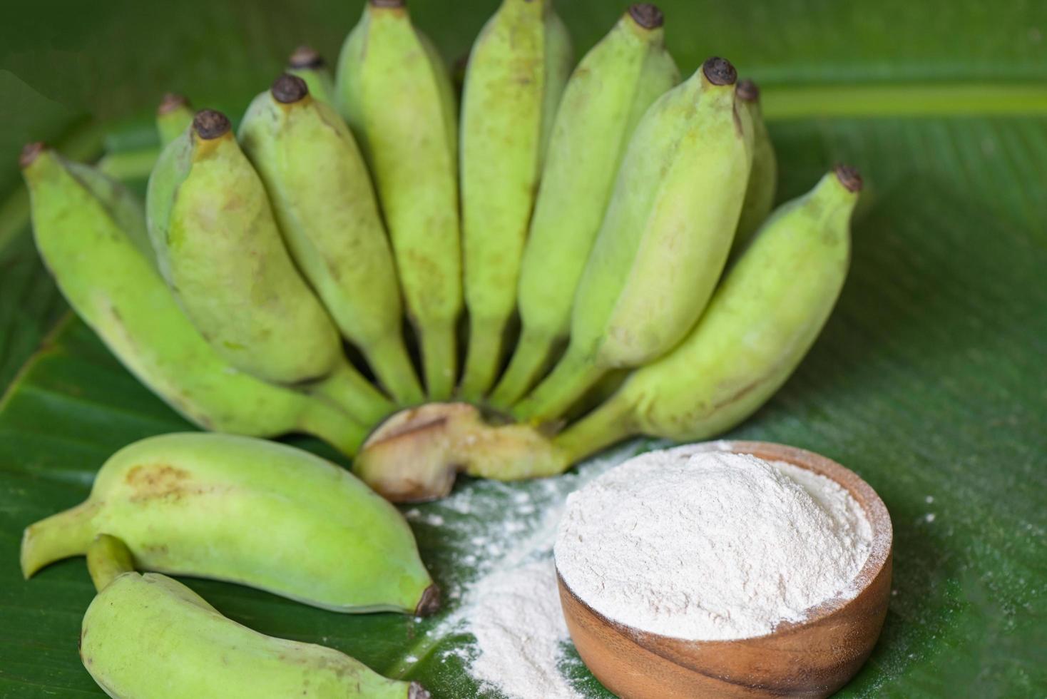 banan pulver på trä- skål och rå banan - banan frukt på blad bakgrund, alternativ mjöl, hemlagad grön banan mjöl för ört- medicin natur ört foto