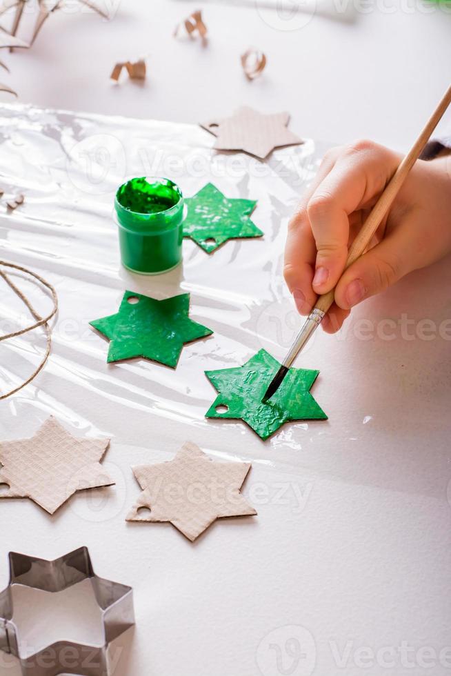 barns händer måla en kartong stjärna för diy jul handgjort dekorationer. vertikal se. foto