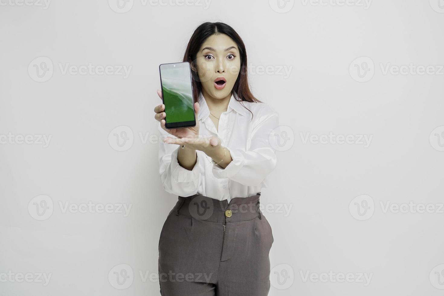 överraskad asiatisk kvinna bär vit skjorta som visar kopia Plats på henne smartphone, isolerat förbi vit bakgrund foto
