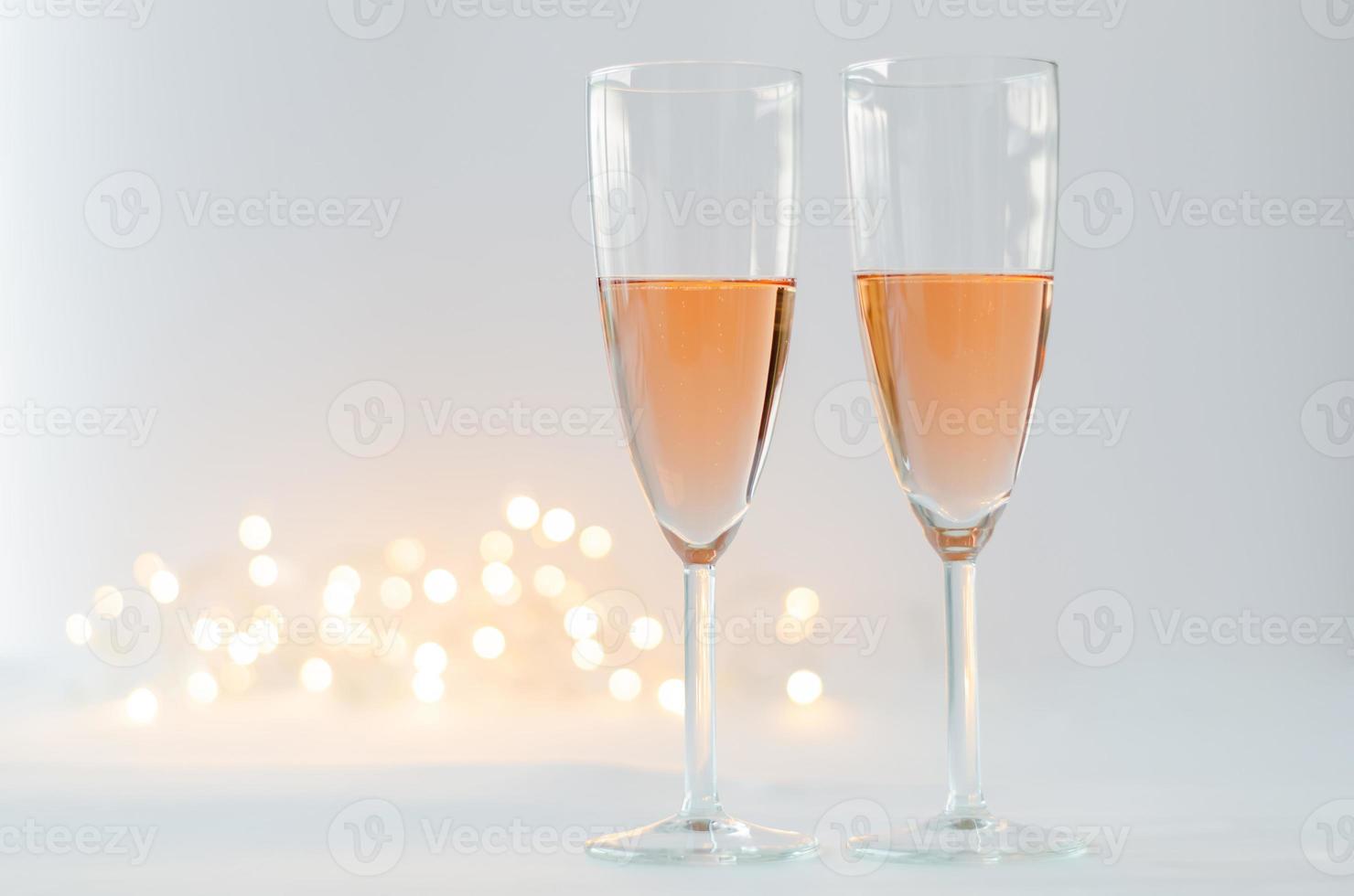 glasögon av gnistrande reste sig vin på vit bakgrund med bokeh ljus för årsdag och valentine dag begrepp. foto