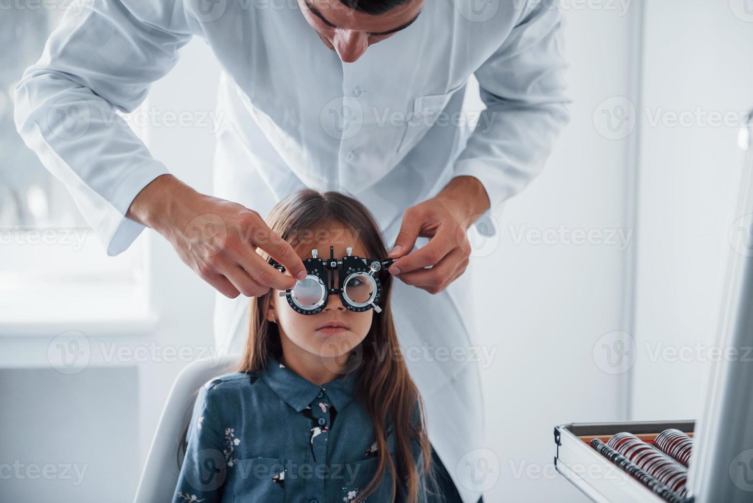 bär diopter. ung ögonläkare är med liten kvinna besökare i de klinik foto