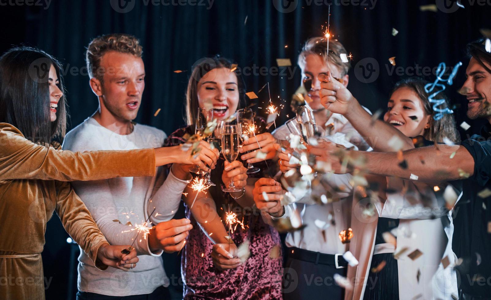 grupp av glad vänner fira ny år inomhus med drycker i händer foto