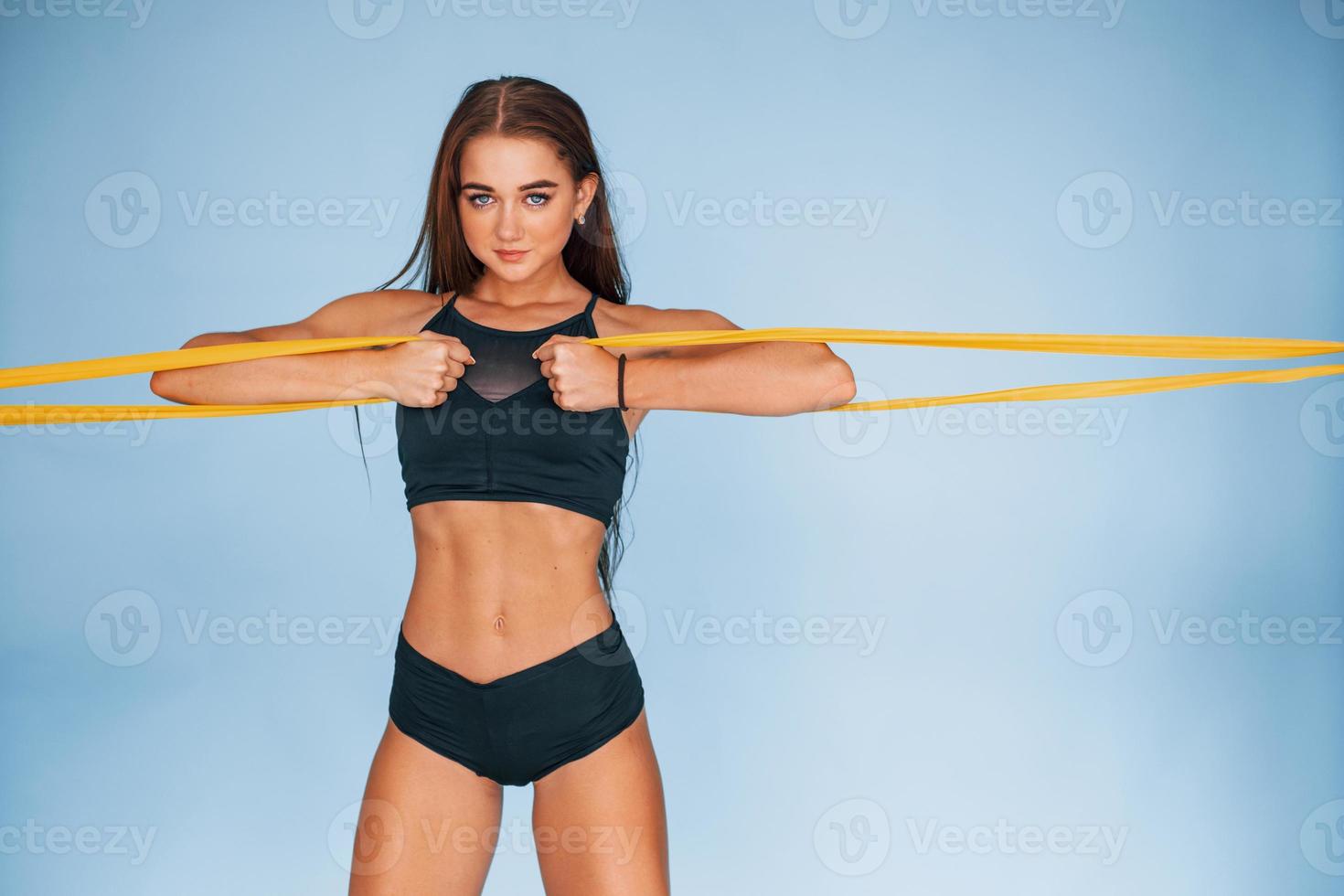 händer övning förbi använder sig av motstånd band. ung kvinna med smal kropp typ isolerat mot blå bakgrund foto