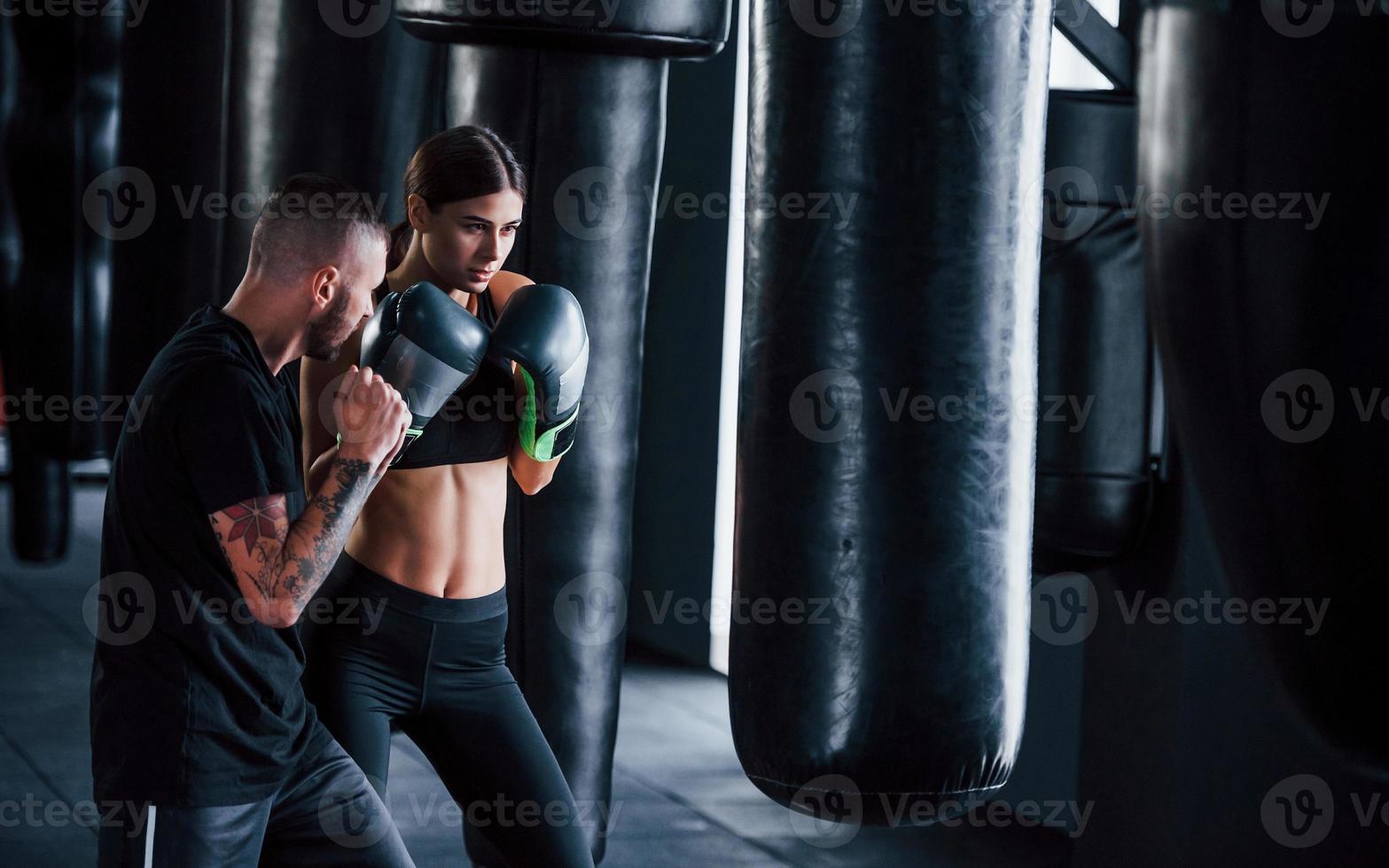 ung tatuerade boxning tränare lär ung kvinna i de Gym foto