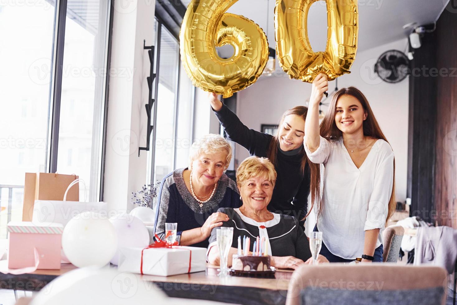 ballonger med siffra 60. senior kvinna med familj och vänner fira en födelsedag inomhus foto