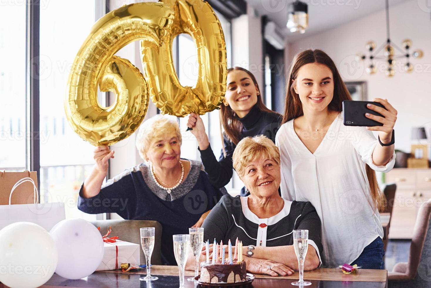 ballonger med siffra 60. senior kvinna med familj och vänner fira en födelsedag inomhus foto