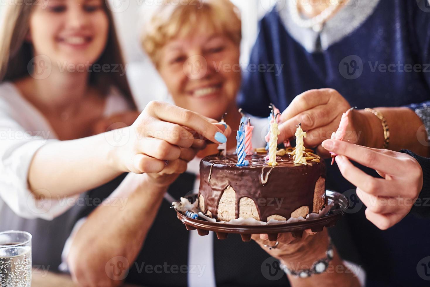 senior kvinna med familj och vänner fira en födelsedag inomhus foto