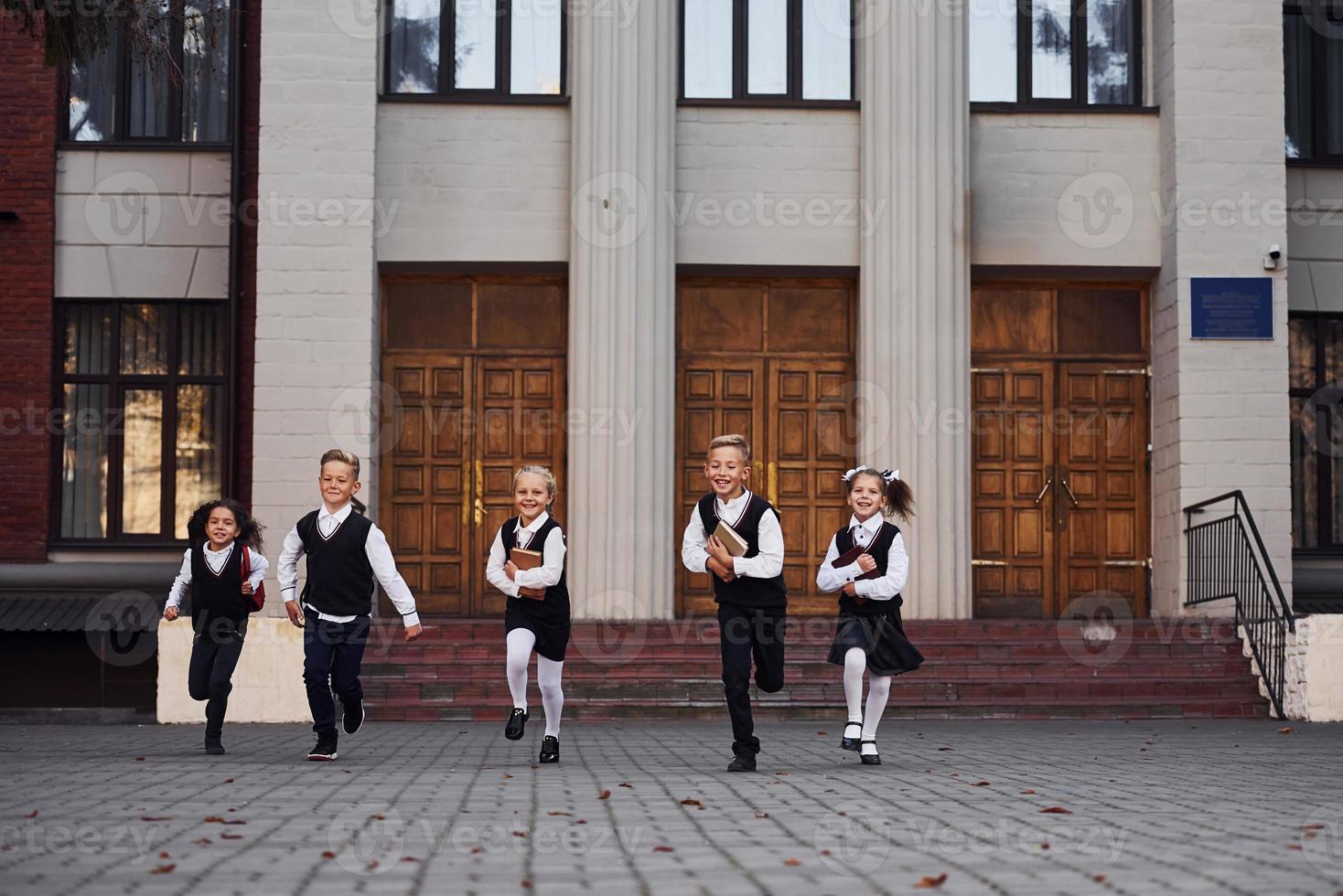 grupp av barn i skola enhetlig den där är löpning utomhus tillsammans foto