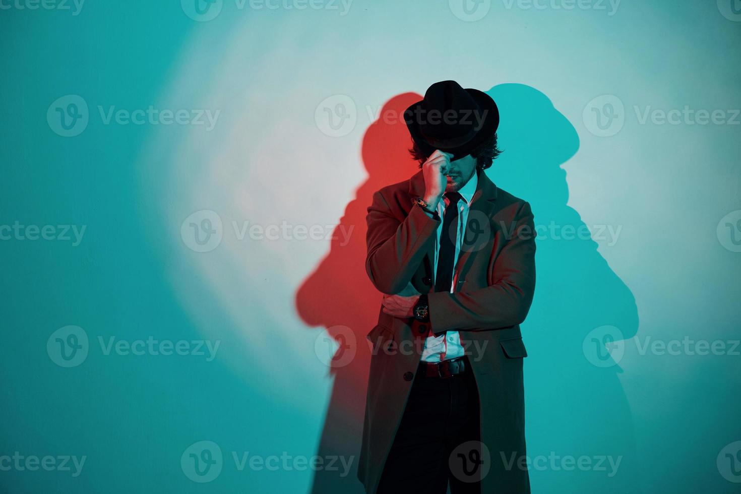 porträtt av ung eleganta man i hatt, kostym och slips den där står i neon lampor i de studio foto
