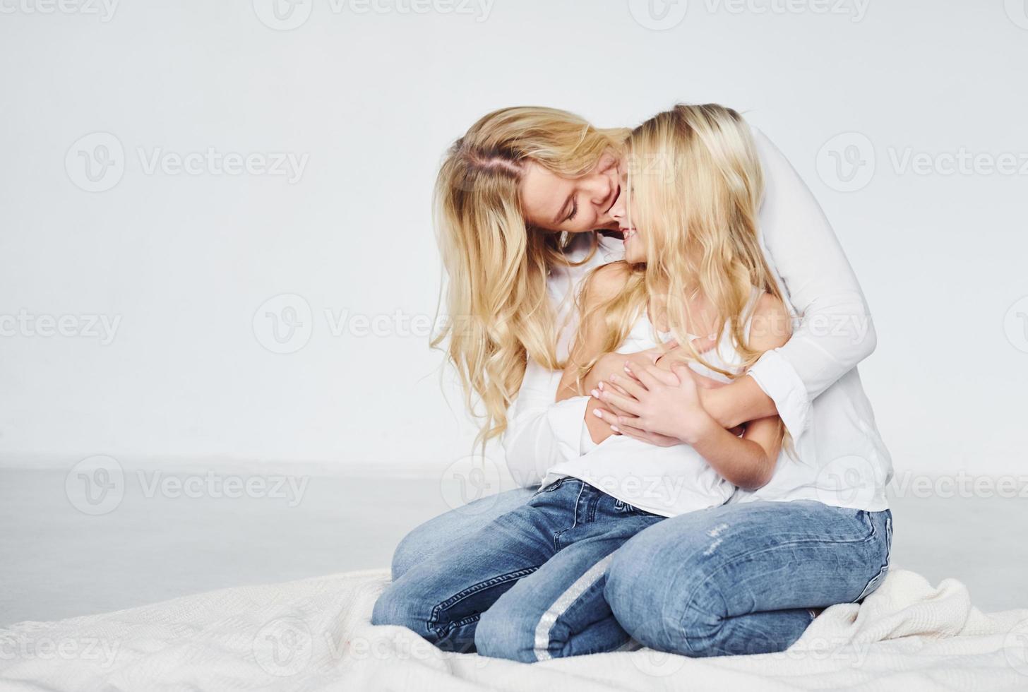 närhet av de människor. mor med henne dotter tillsammans i de studio med vit bakgrund foto