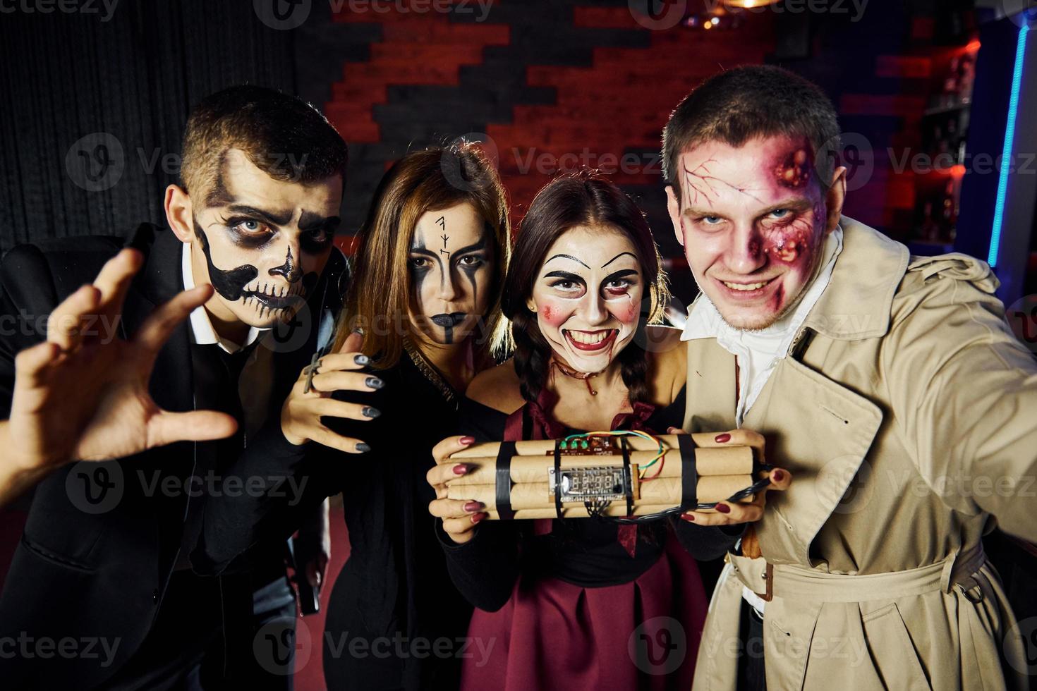 vänner med bomba i händer är på de tematiska halloween fest i skrämmande smink och kostymer foto