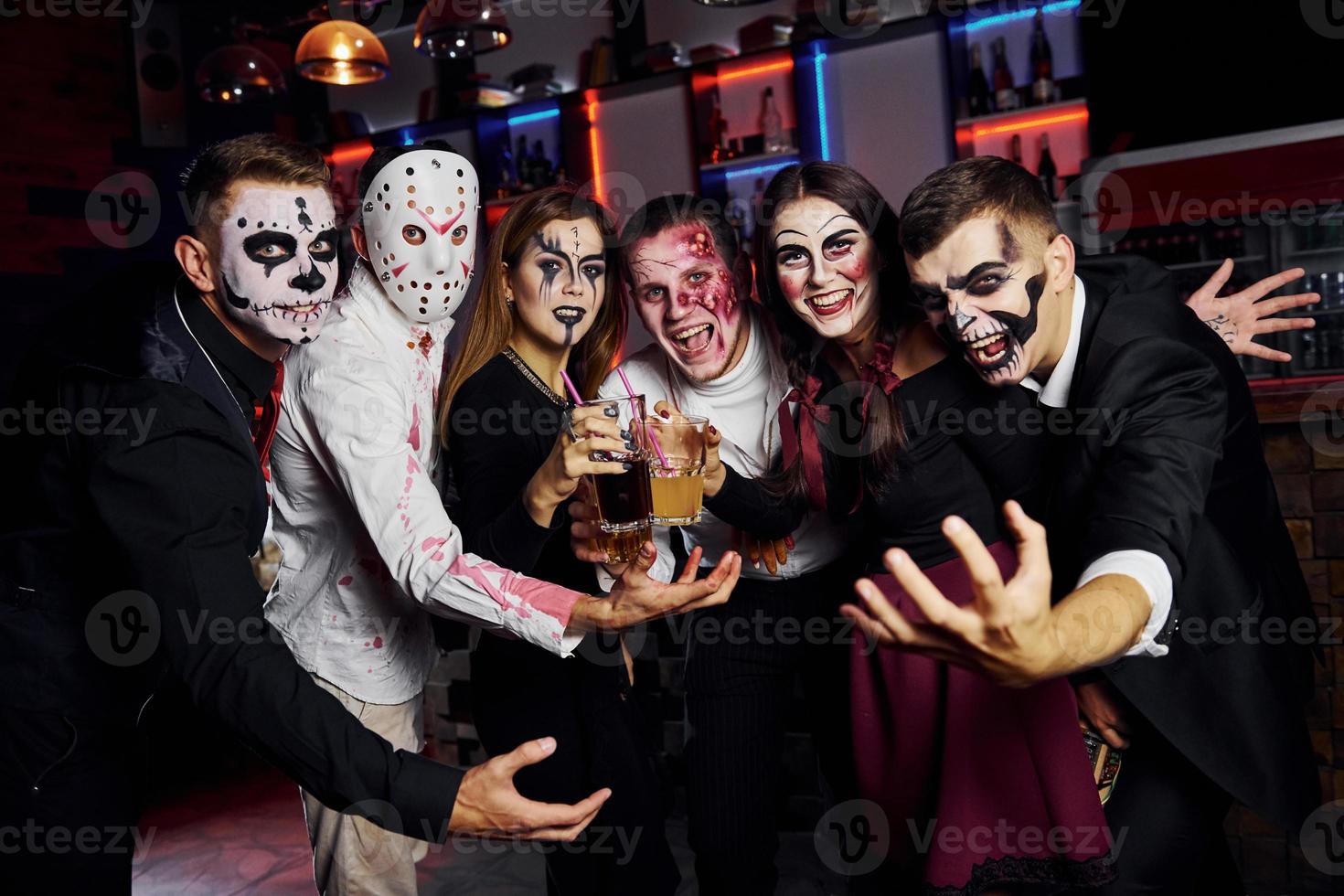 Framställ för de kamera. vänner är på de tematiska halloween fest i skrämmande smink och kostymer foto