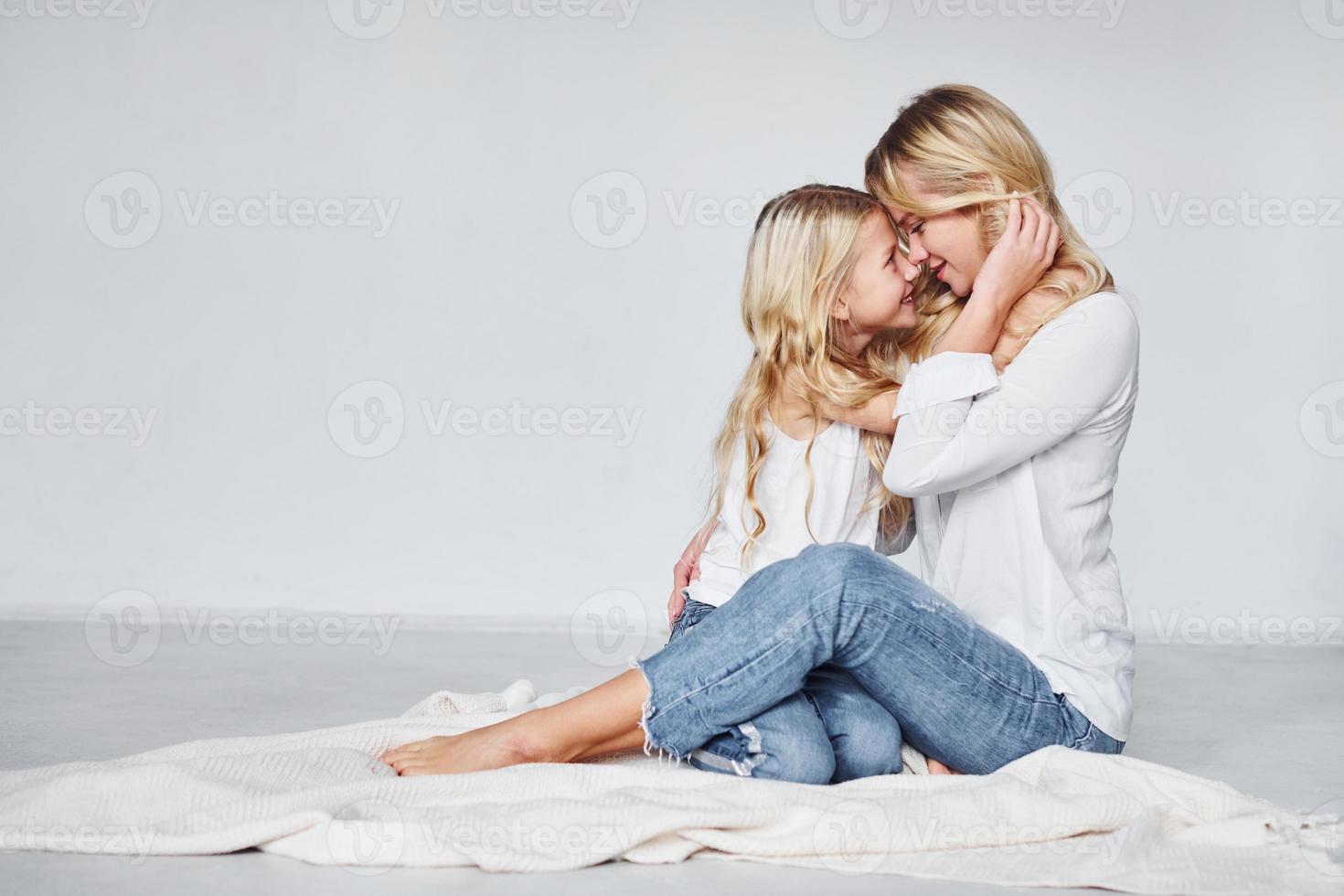 mor med henne dotter tillsammans är på de jord i de studio med vit bakgrund foto