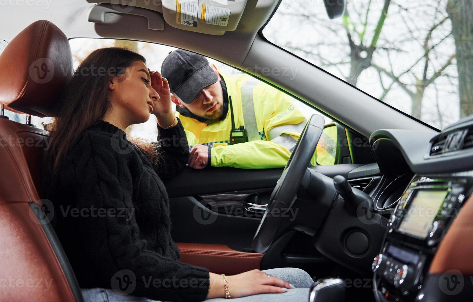 flickor känner dålig. manlig polis officer i grön enhetlig kontroll fordon på de väg foto