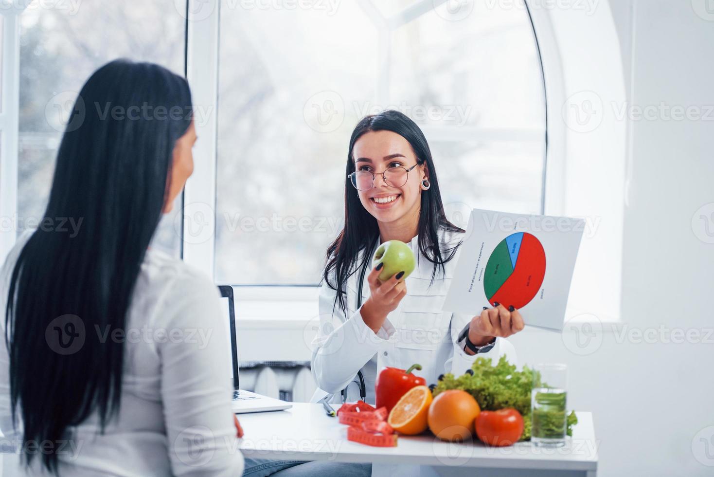 kvinna dietist med Graf ger samråd till patient inomhus i de kontor foto