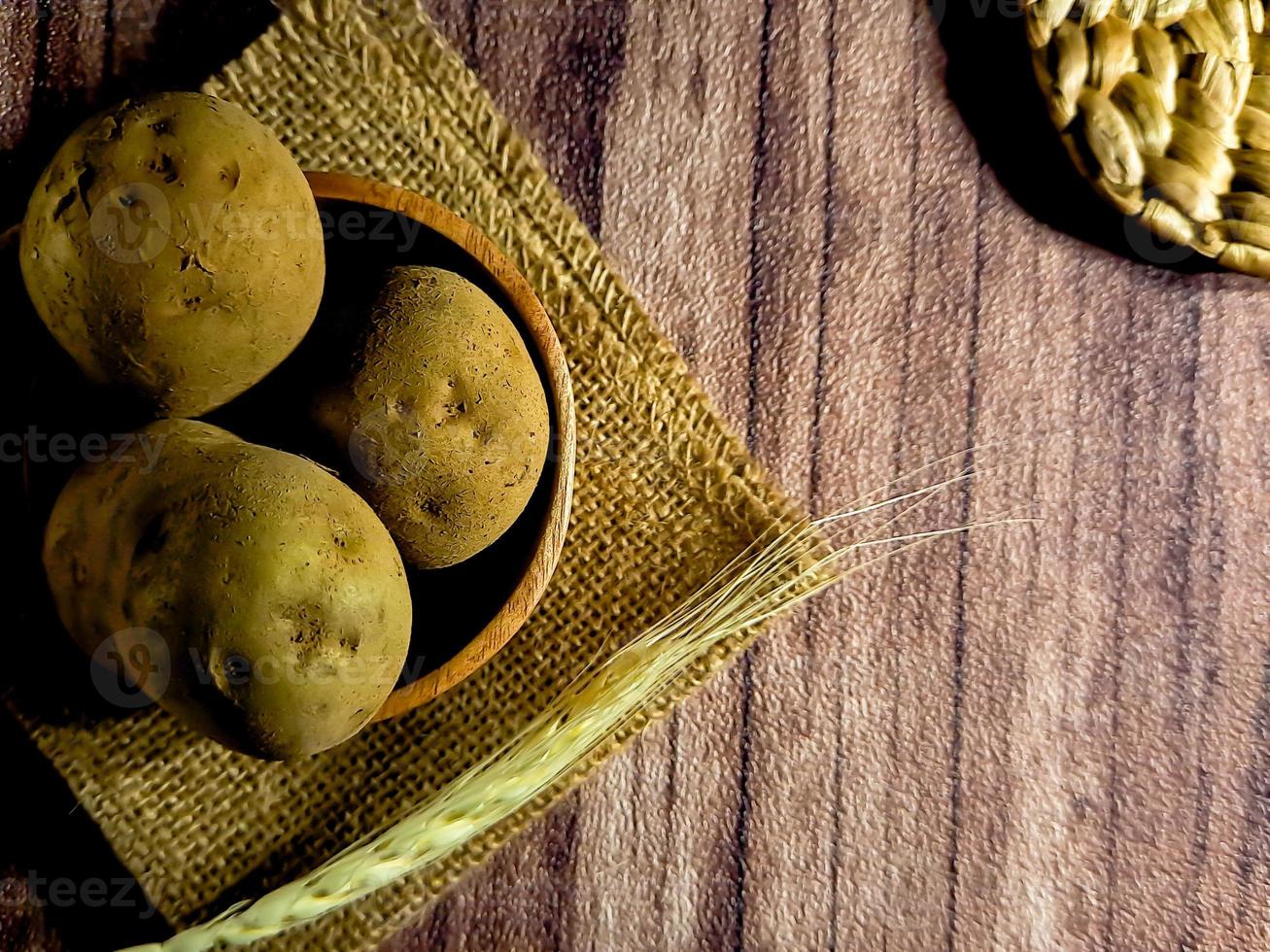 lugg av rå potatisar på mörk trä- bakgrund. förberedelse av potatis soppa eller maträtt, perfekt för reklam broschyr bakgrund foto