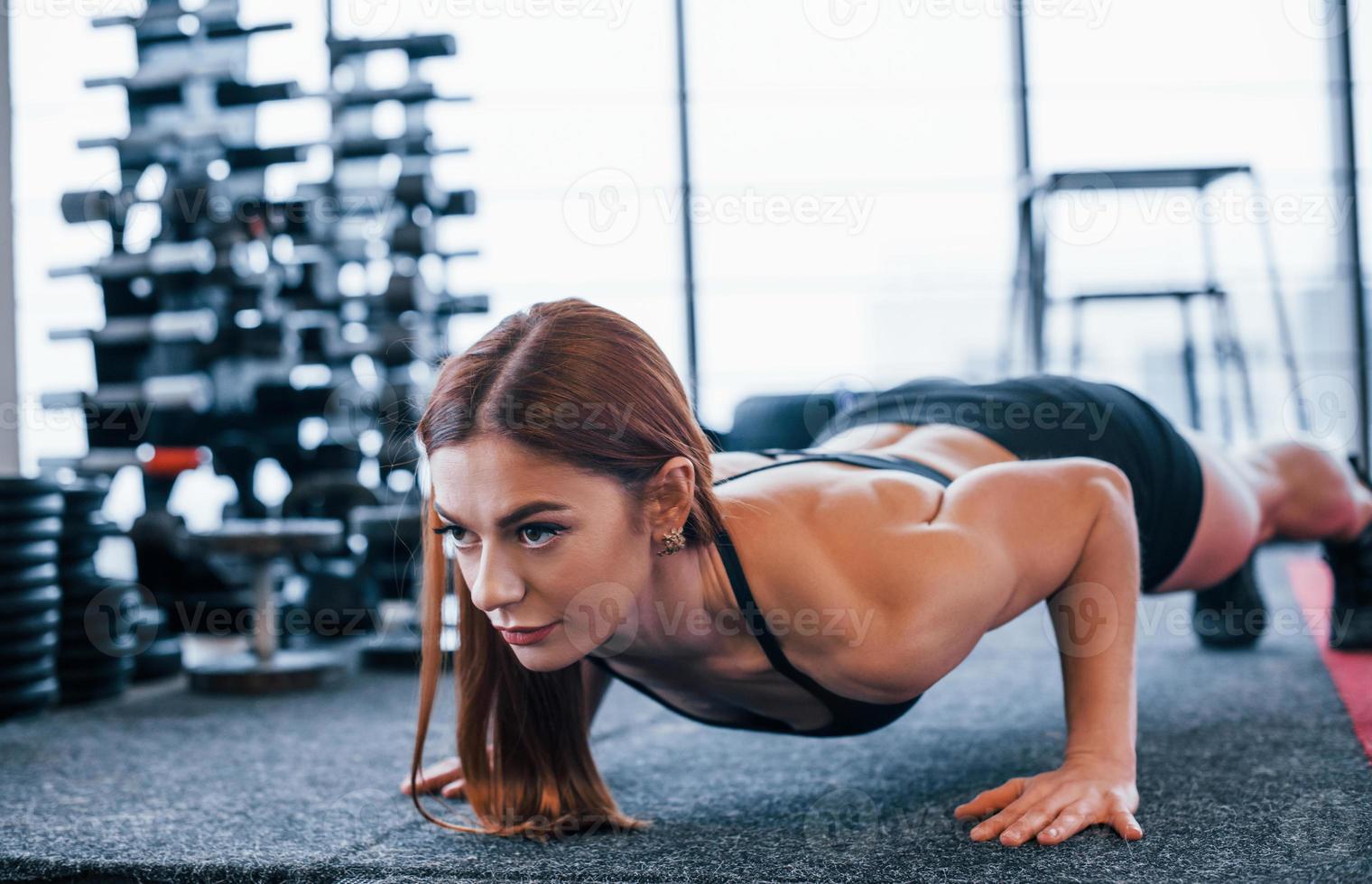 ung sportigt kvinna i svart kläder håller på med skjuta på Posten i de Gym foto