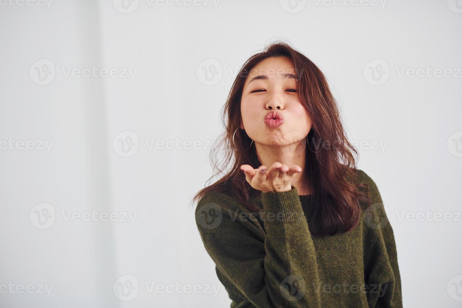 porträtt av Lycklig asiatisk ung flicka den där stående inomhus i de studio mot vit bakgrund foto