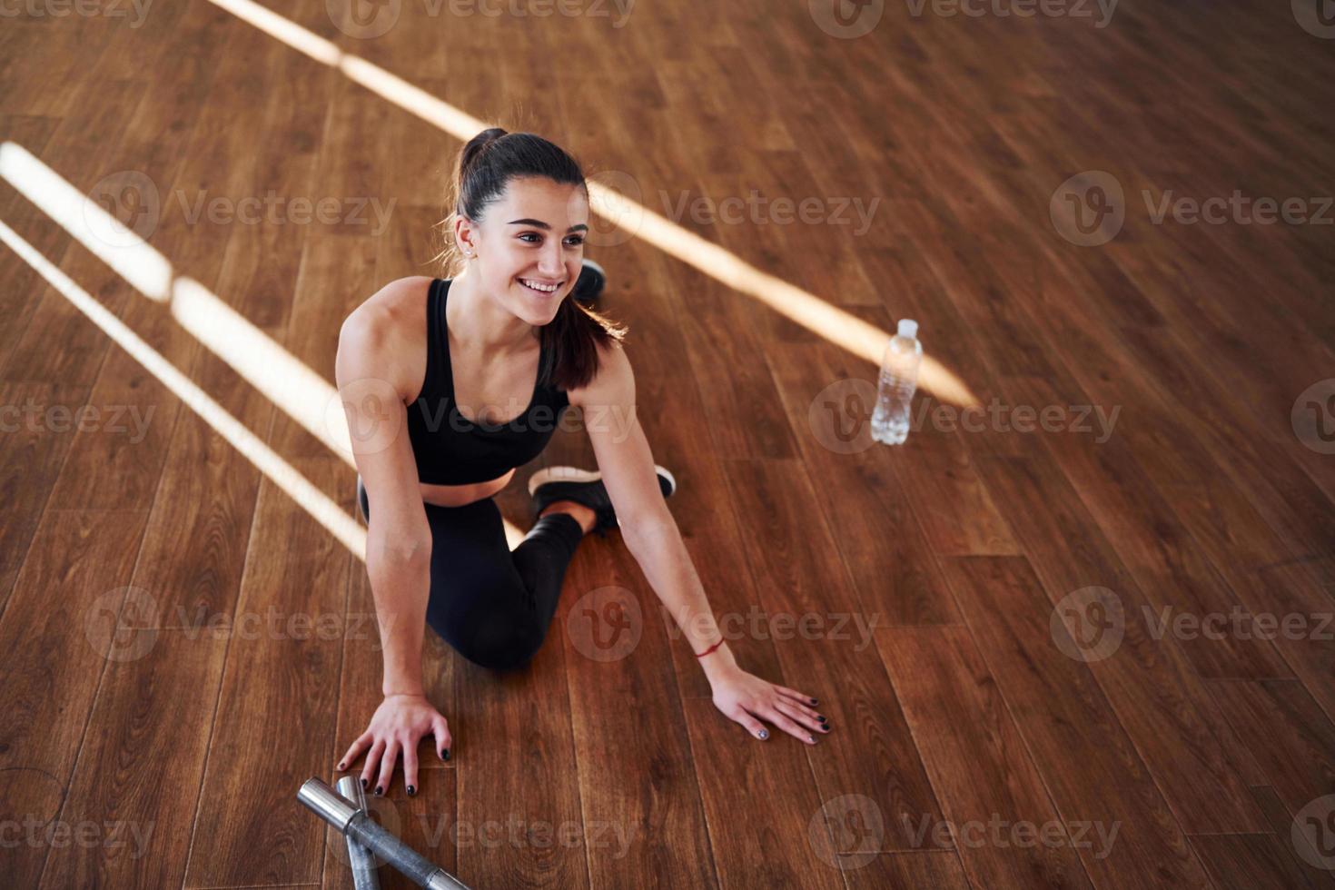 på de golv upplyst förbi ljus strålar. ung sportig kvinna i sportkläder håller på med kondition i de Gym foto