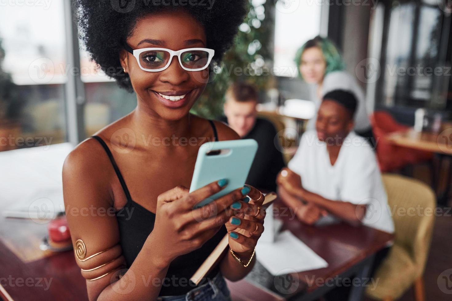 svart kvinna stående i främre av grupp av mång etnisk människor med alternativ flicka med grön hår är arbetssätt tillsammans förbi de tabell inomhus foto