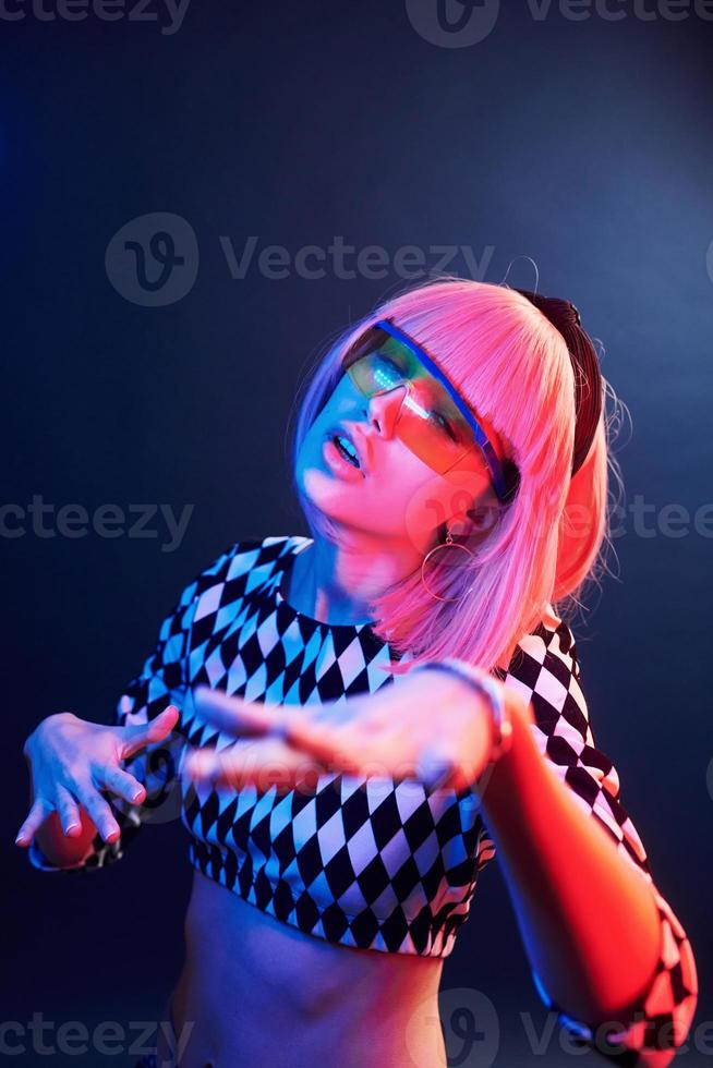 porträtt av ung flicka med blond hår i glasögon i röd och blå neon i studio foto