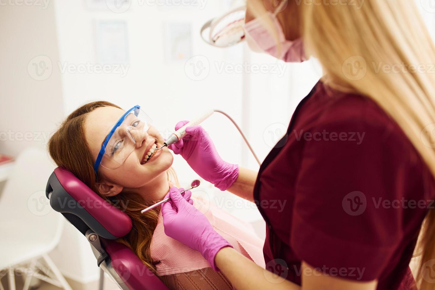 liten flicka i skyddande glasögon besöker tandläkare i klinik. uppfattning av stomatologi foto