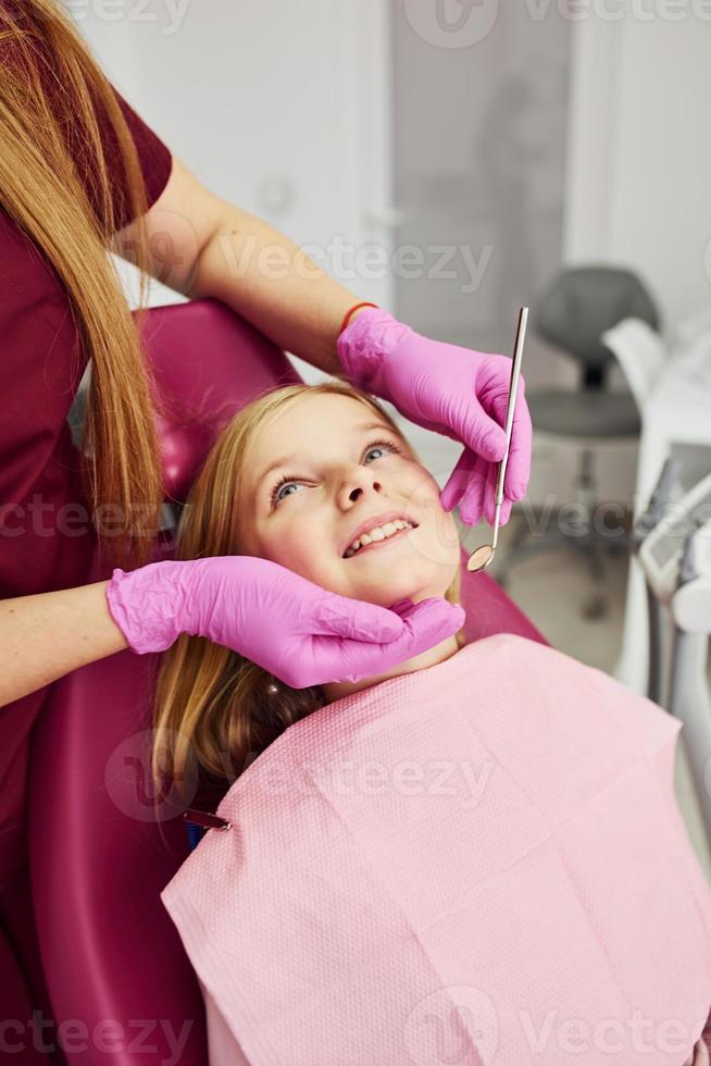 liten flicka besöker tandläkare i klinik. uppfattning av stomatologi foto