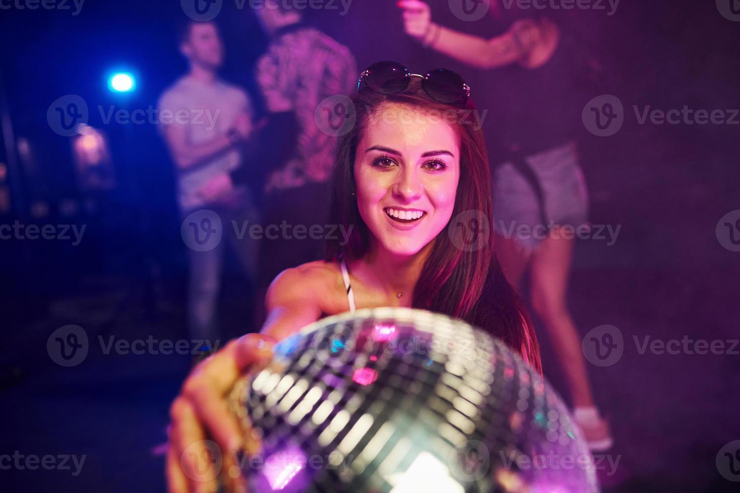 flicka Sammanträde inuti av natt klubb med fest boll i händer foto