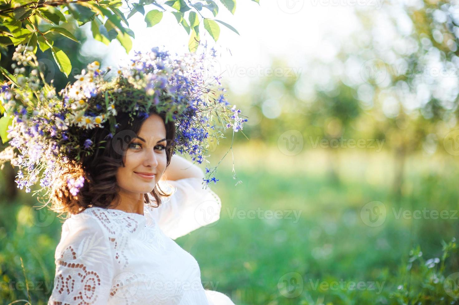 skön ung kvinna med blomma krans i de trädgård foto