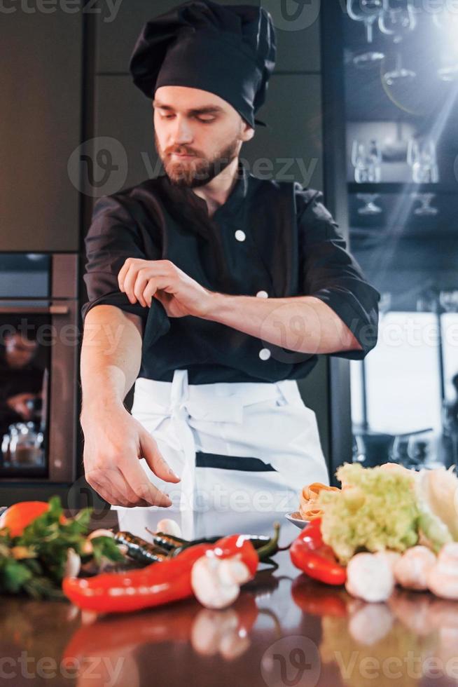 professionell ung kock laga mat i enhetlig ha en upptagen dag på de kök foto