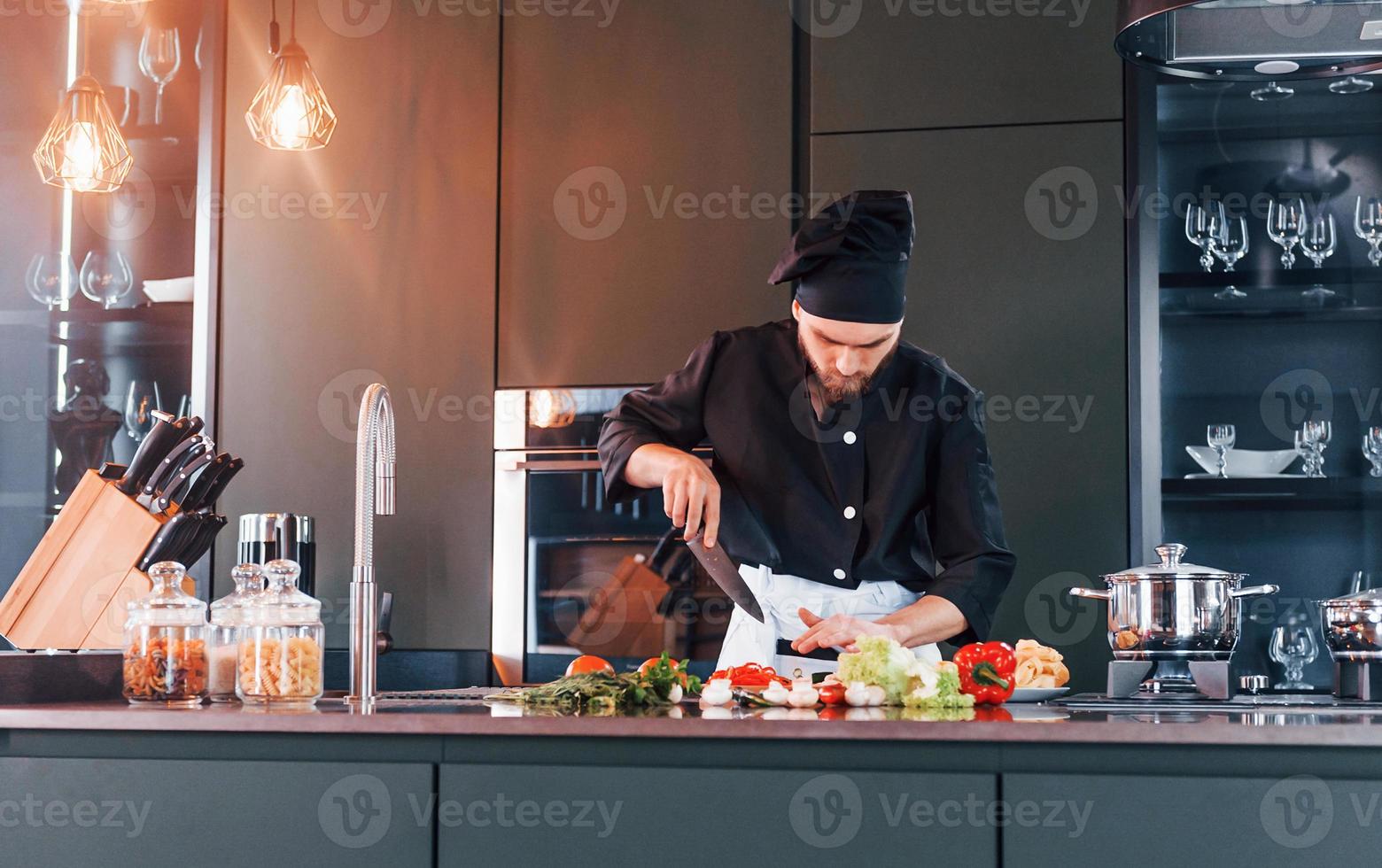 professionell ung kock laga mat i enhetlig arbetssätt på de kök foto