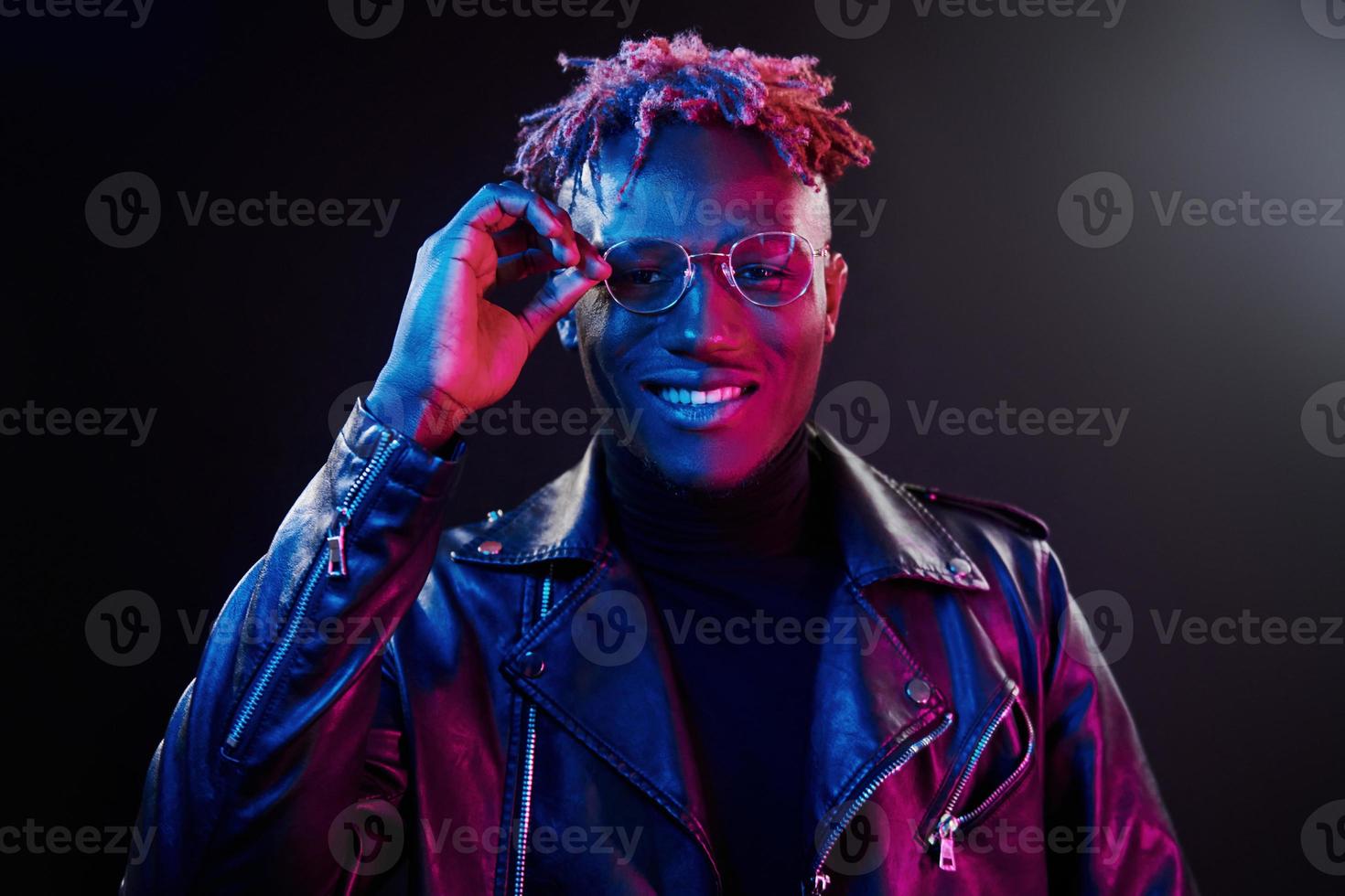 trogen neon belysning. ung afrikansk amerikan man i glasögon stående i studio foto