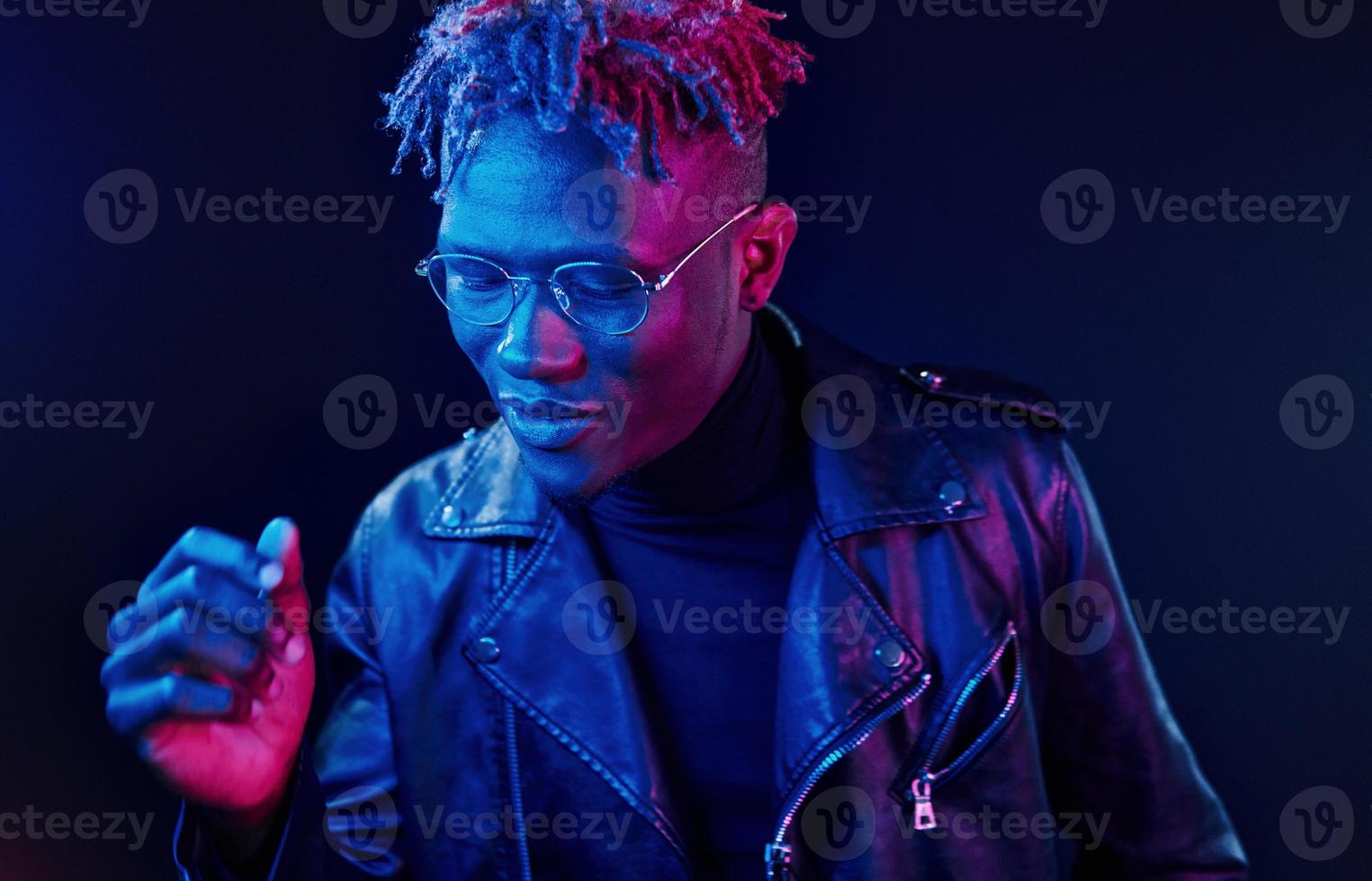 har roligt. trogen neon belysning. ung afrikansk amerikan man i de studio foto