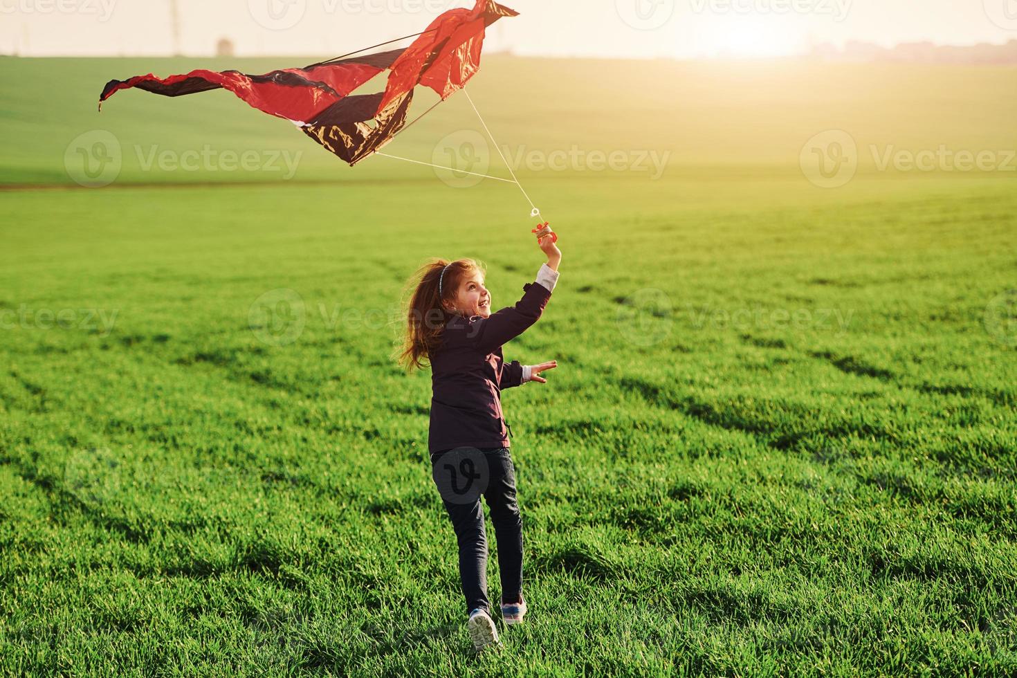 Lycklig liten flicka löpning med kate i händer på de skön fält foto