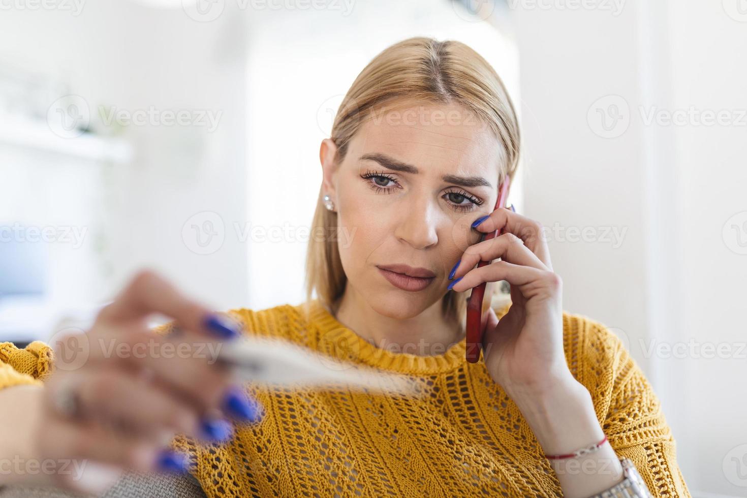 ung kvinna är ser på de termometer. hon har feber, kallelse henne läkare. skön kvinna med symptom kallad covid-19 nödsituation siffra till Rapportera henne medicinsk betingelser foto