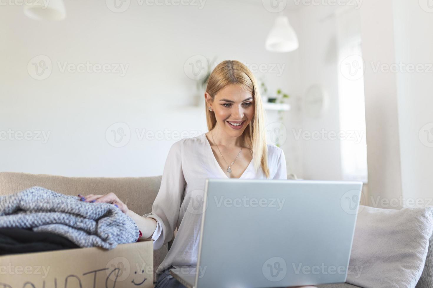 donation begrepp. kvinna innehav en donera låda med full av kläder. kvinna innehav en bok och kläder donera låda. kläder i låda för begrepp donation och återanvändning återvinna foto