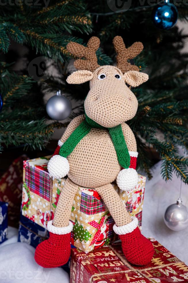 stickat älg. söt älg. leksak mot de bakgrund av en ny år krans, stickat hare och älg på en jul träd foto