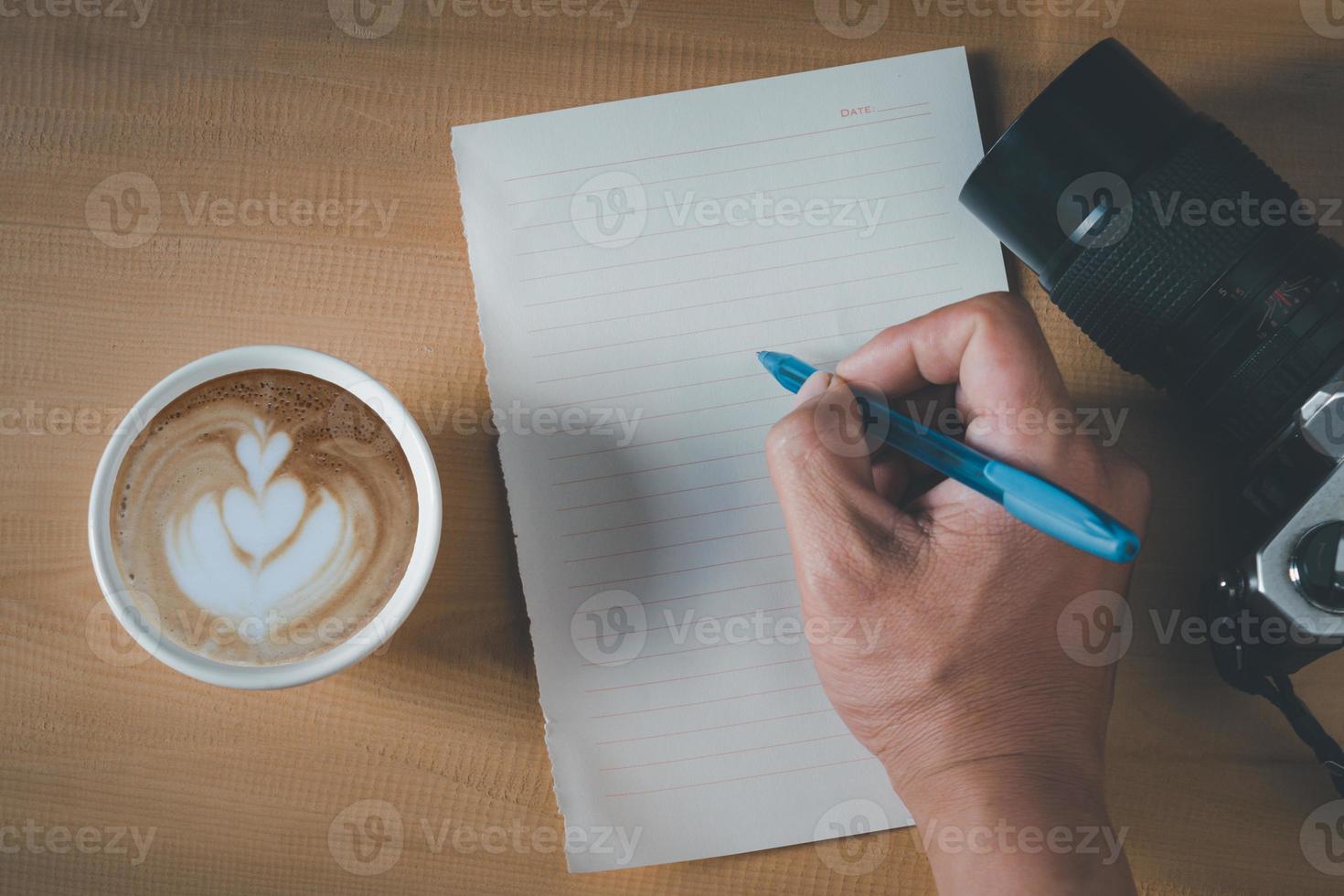 topp se av tömma papper, kaffe kopp, kamera och penna på de trä- tabell foto