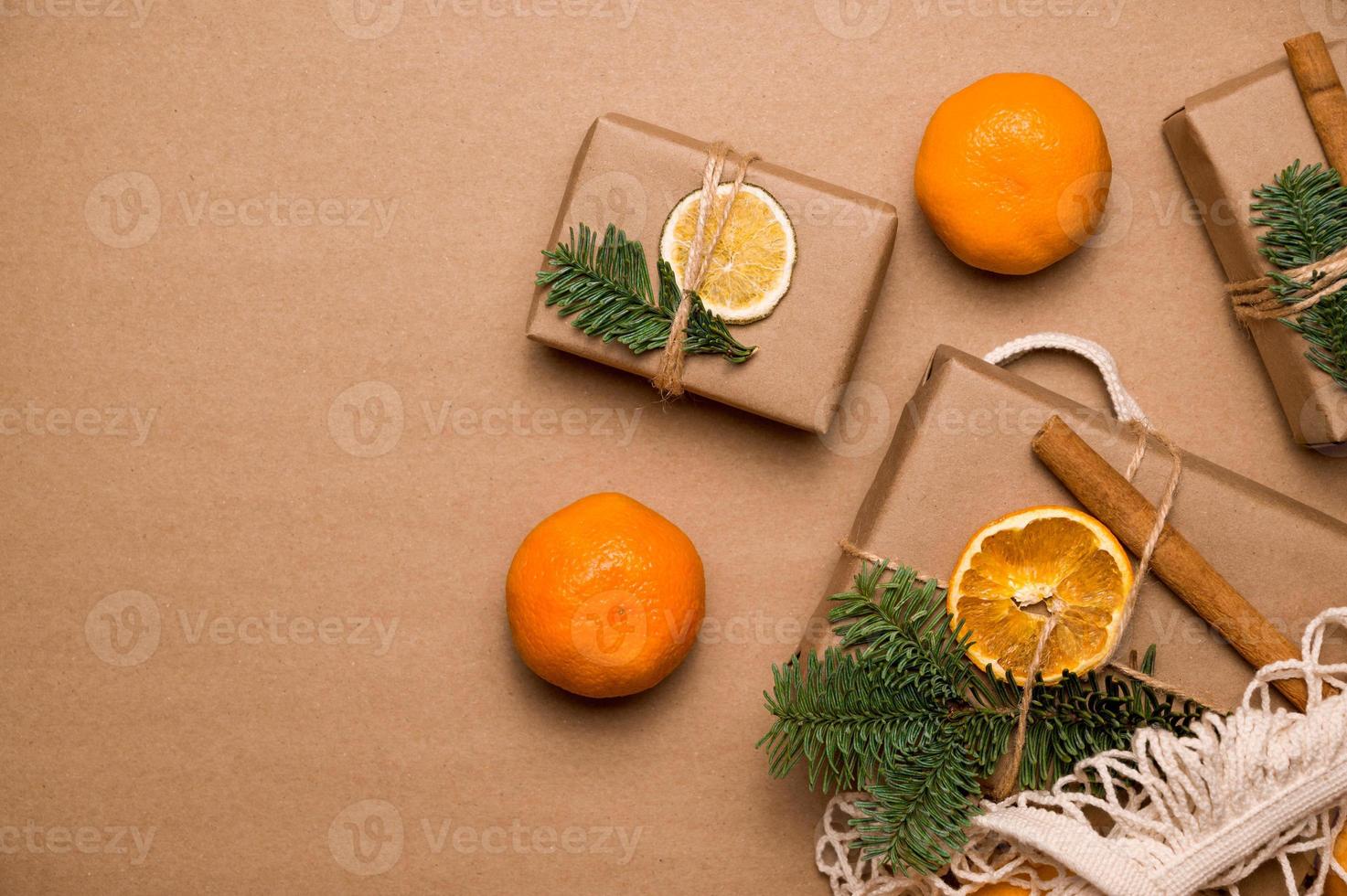 jul eller ny år flatlay i naturlig toner. gåvor i hantverk papper dekarerad witn kanel, apelsiner och gran nära mandariner.eco vänlig och noll avfall begrepp. foto