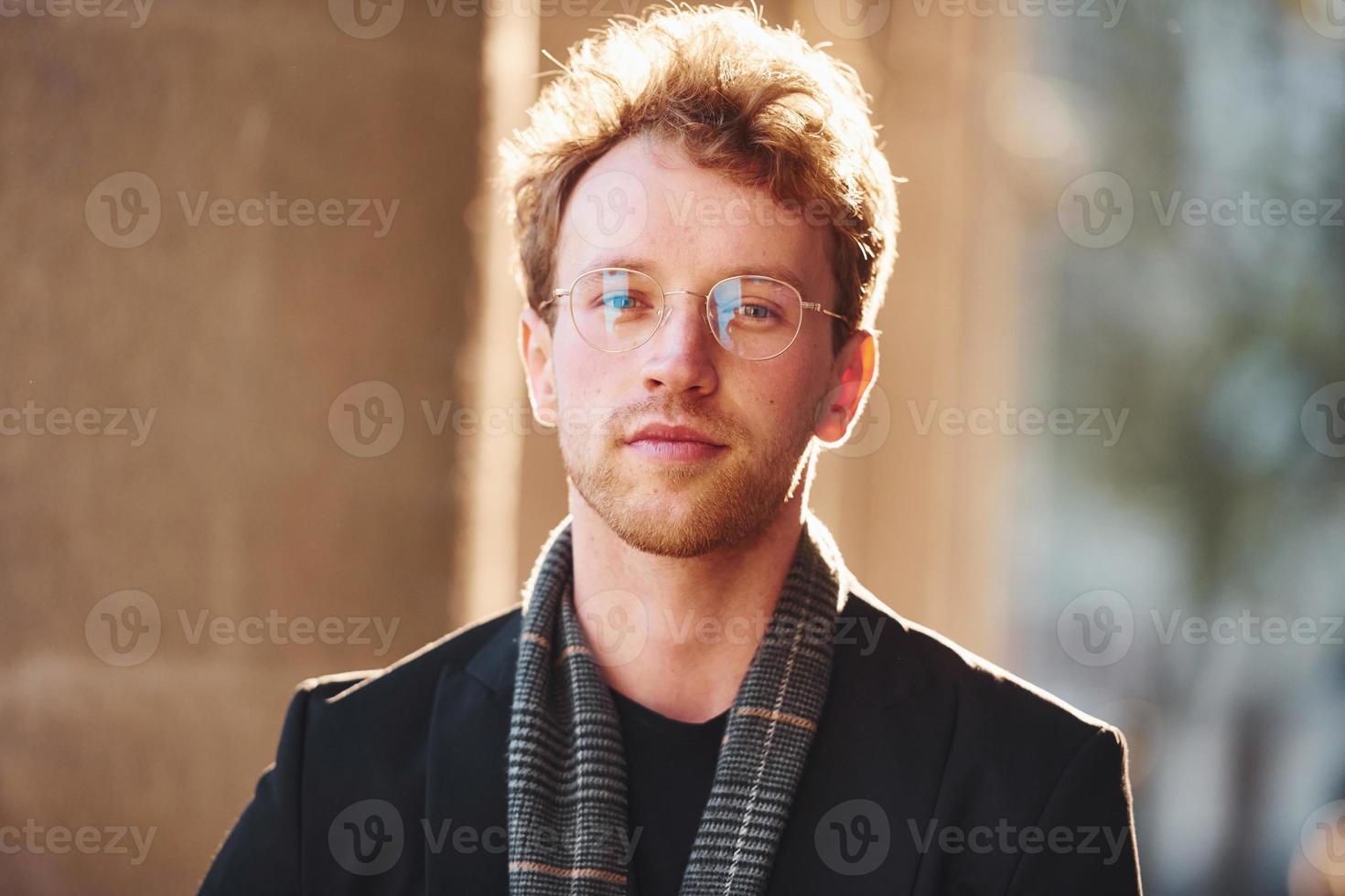 porträtt av elegant ung man i glasögon och formell flott kläder utomhus i de stad foto