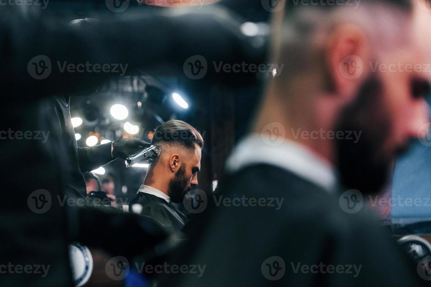 ung skäggig man Sammanträde och få frisyr i barberare affär foto