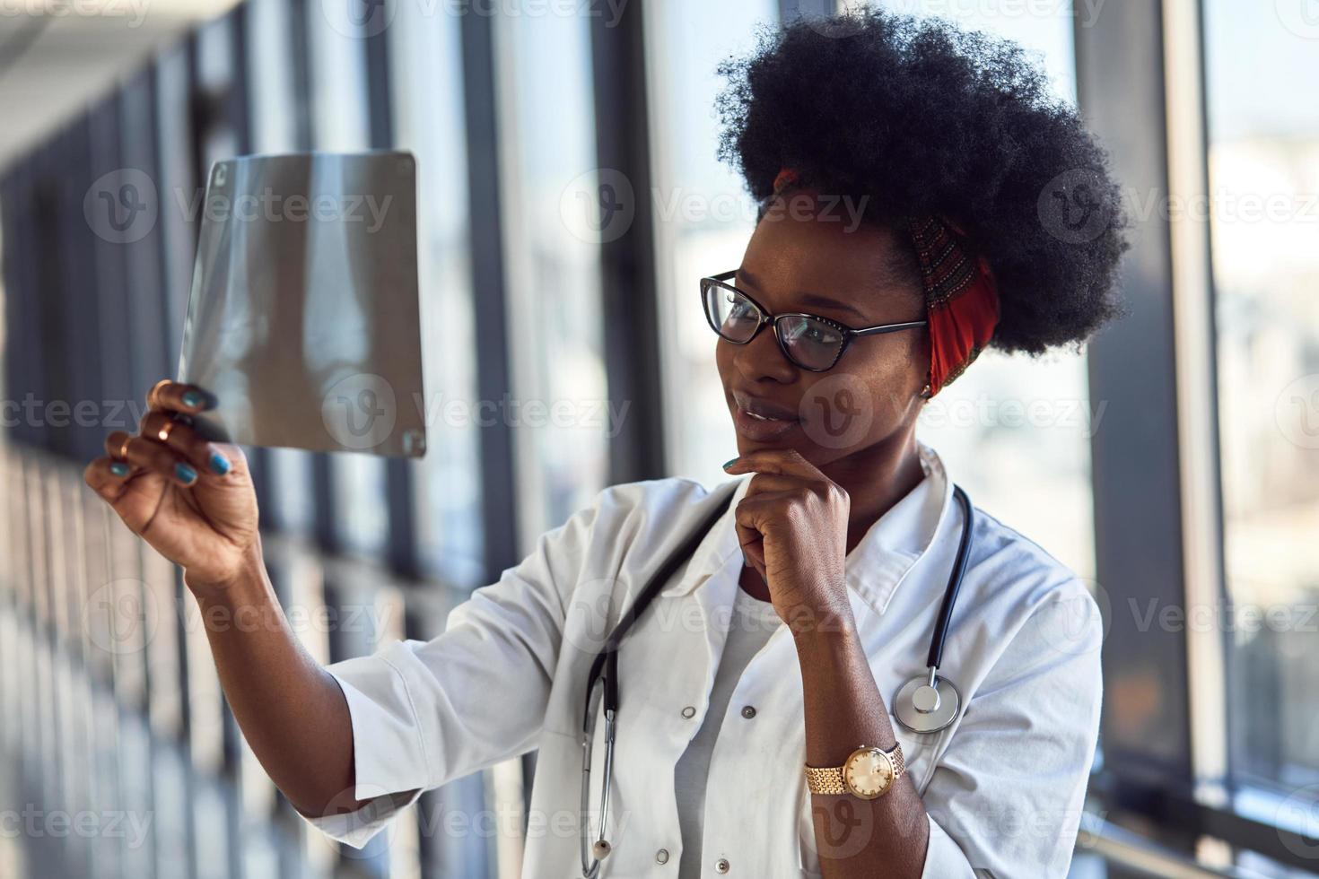 ung afrikansk amerikan kvinna läkare i vit enhetlig utseende på röntgen foto