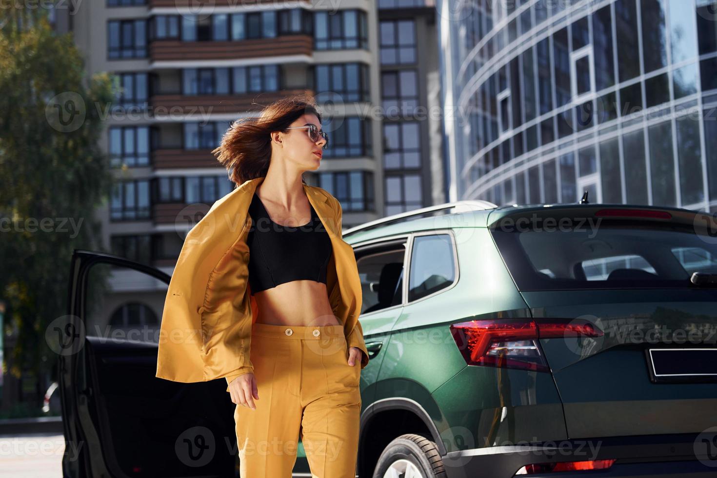 promenader framåt- från bil. ung modern kvinna i vinröd färgad täcka på dagtid med henne bil foto