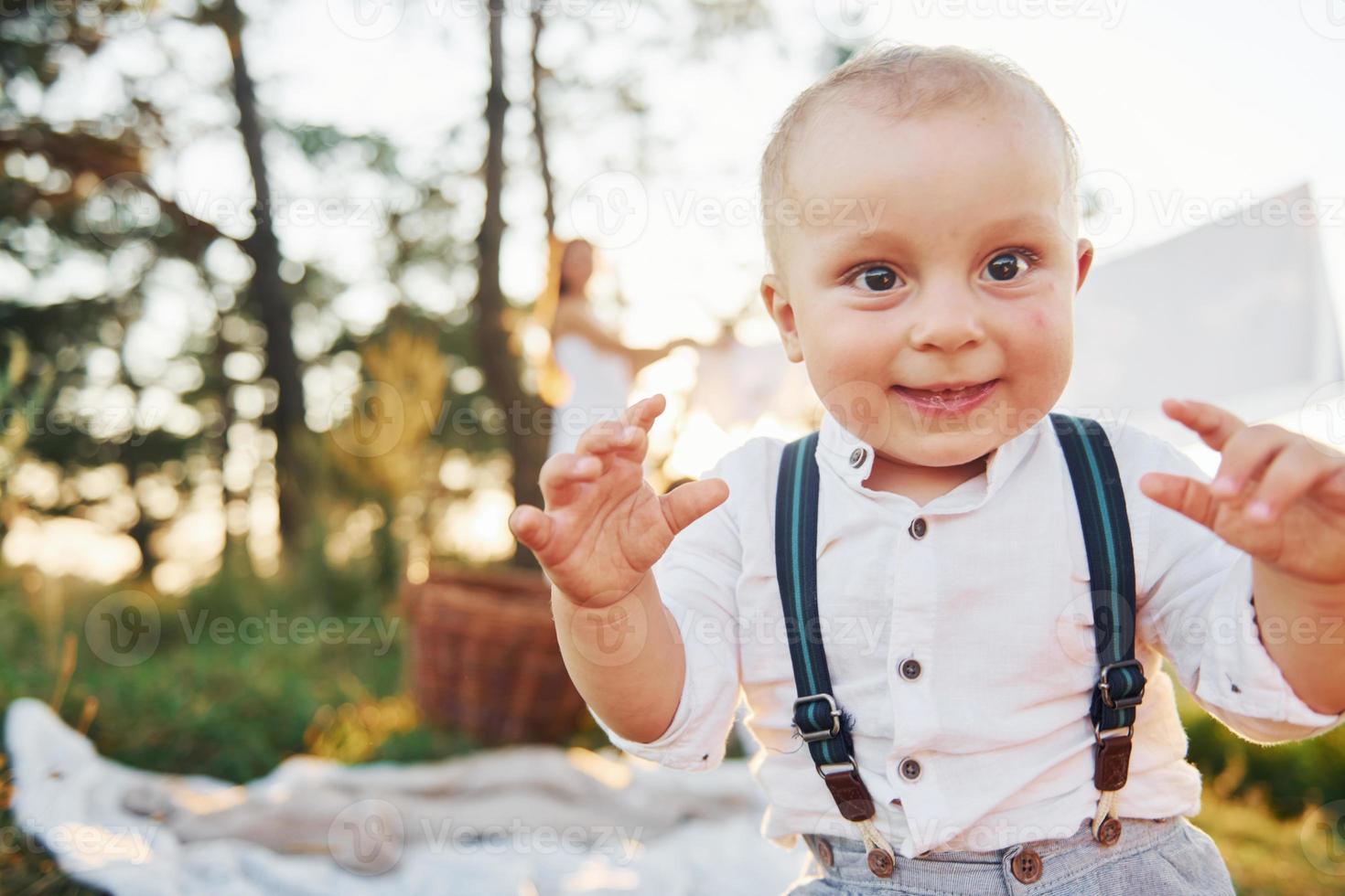 positiv pojke leende på de kamera. ung mor med henne liten son är utomhus i de skog. skön solsken foto