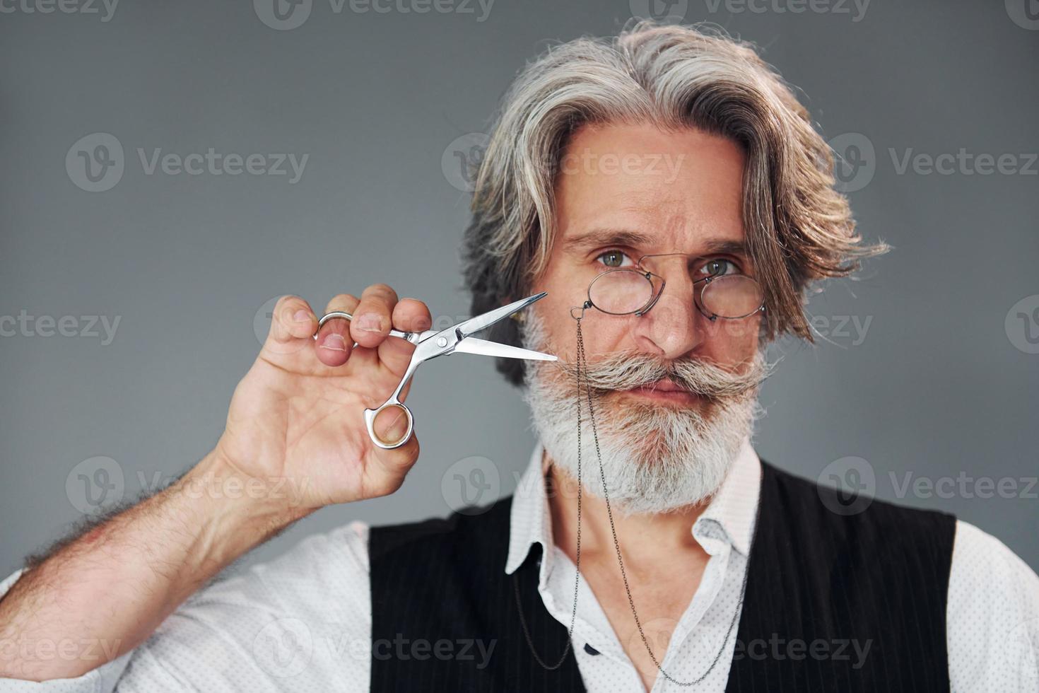 frisör verktyg. mot grå bakgrund. eleganta modern senior man med grå hår och skägg är inomhus foto