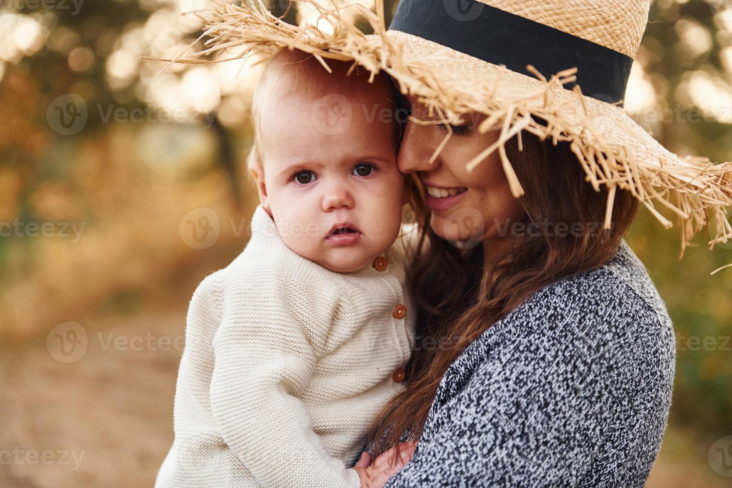 ung mor med henne liten bebis vilar utomhus på höst säsong foto